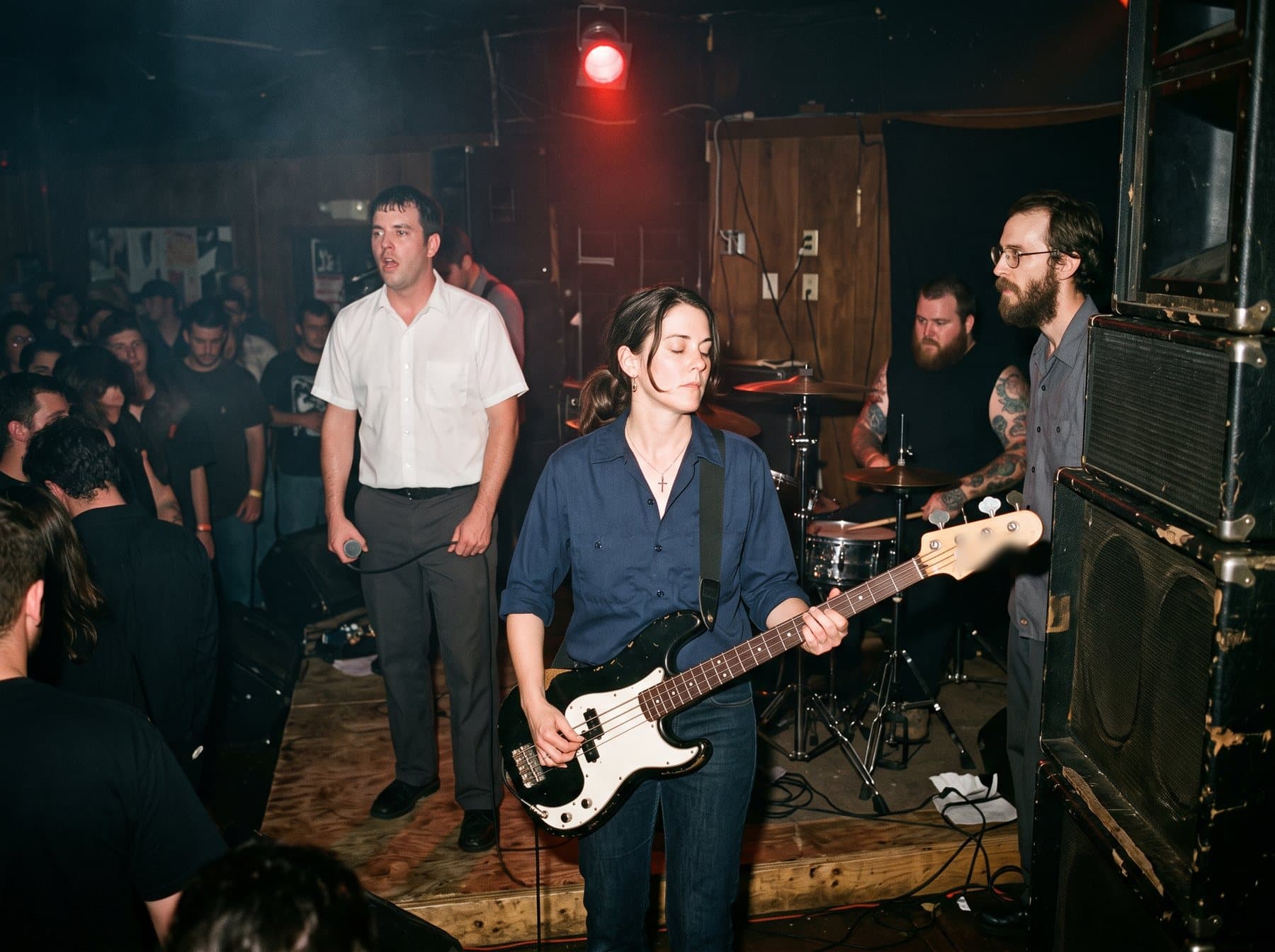 A woman bassist and a guitarist playing under a single red light on a low stage in a small Southern club